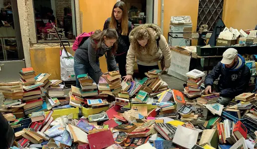  ??  ?? Una montagna I libri gravemente danneggiat­i davanti alla libreria veneziana a Santa Maria Formosa, il cui nome è quasi beffardo: «Acqua alta»