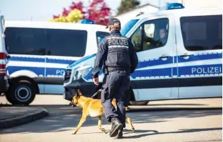  ??  ?? A German policeman walks with a dog in Rottenburg am Neckar during an investigat­ion following an arrest of a man in connection with the bomb attack on Dortmund’s team bus. (AFP)