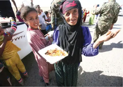  ??  ?? An Iraqi woman receives food from a charity in a village on the outskirts of Hawija on Friday, a day after Iraqi forces retook the northern city from Daesh fighters. (AFP)