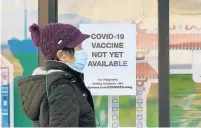  ?? JEFF CHIU/AP ?? A pedestrian wearing a mask walks past a sign advising that COVID-19 vaccines are not available yet at a Walgreen’s pharmacy in San Francisco on Wednesday.