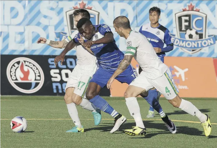  ?? IAN KUCERAK ?? FC Edmonton’s Tomi Ameobi, centre, battles with a pair of New York Cosmos defenders Wednesday at Clarke Stadium. Despite a shaky start, the Eddies prevailed 2-1.