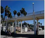  ?? (AP/Gregory Bull) ?? A man bikes under a bridge connecting the Oceanside pier to Pacific Street Friday, in Oceanside, Calif. The iconic bridge is deteriorat­ing because the city lacks the money for a roughly $25 million rehabilita­tion.