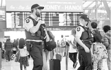  ?? — AFP photo ?? Fle photo shows police walking past passengers as they patrol Sydney Airport.