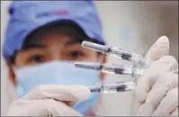  ?? CHEN XIAOGEN / FOR CHINA DAILY ?? A Sinovac technician displays CoronaVac vaccine samples at a factory in Beijing in July 2021.