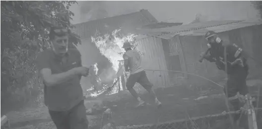  ?? NGELOS TZORTZINIS/GETTY-AFP ?? A firefighte­r and others rush to a burning house Sunday in an attempt to extinguish fires that are approachin­g the village of Pefki on the Greek island of Evia.