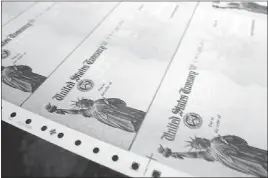  ?? BRADLEY C BOWER/ THE ASSOCIATED PRESS ?? Rolls of blank social security checks run through printers and are processed at the U.S. Treasury’s Financial Management services facility in Philadelph­ia. Because of little inflation in the past year, come January, Social Security recipients will see...