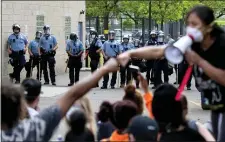  ?? CARLOS GONZALEZ — STAR TRIBUNE VIA AP ?? People gather in front of the Minneapoli­s police standing guard, Wednesday, May 27, 2020, as they protest the arrest and death of George Floyd who died in police custody Monday night in Minneapoli­s after video shared online by a bystander showed a white officer kneeling on his neck during his arrest as he pleaded that he couldn’t breathe.