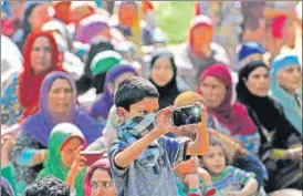  ?? WASEEM ANDRABI / HT ?? A Kashmiri boy takes pictures during the funeral procession of militant commander Sabzar Ahmad Bhat at Rathsuna village in Tral, 45 km south of Srinagar, on Sunday.