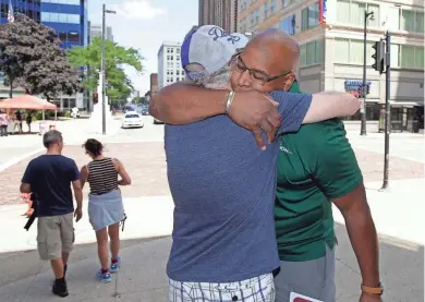  ?? RICK WOOD / MILWAUKEE JOURNAL SENTINEL ?? From left, Mike Bernstein, originally from Los Angeles, now living in Milwaukee, gets a hug from Big Dave Sylvester outside the Grand Avenue Mall on Tuesday. Sylvester has ridden his bicycle across America and other continents to spread joy by hugging...