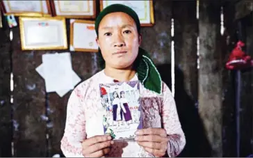  ?? NHAC NGUYEN/AFP ?? Vu Thi Dinh, a Vietnamese mother, poses with a photograph of her missing teenage daughter Dua at her house in a mountainou­s border district in Vietnam’s Ha Giang province across from China.