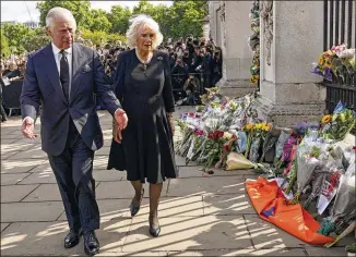  ?? YUI MOK/POOL PHOTO VIA AP ?? King Charles III and Camilla, the queen consort, walk past floral tributes outside London’s Buckingham Palace following the death of his mother, Queen Elizabeth II. Charles married Camilla Parker Bowles nearly nine years after he divorced Princess Diana and eight years after her death.