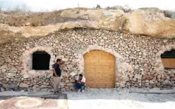  ??  ?? Ahmed Amarneh and a neighbor chat outside his home, built in cave.