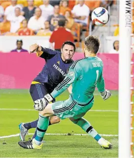  ?? Bob Levey ?? Dynamo goalkeeper Tyler Deric makes a stop on a shot by the Galaxy’s Robbie Keane in the first half of Saturday night’s game at BBVA Compass Stadium.