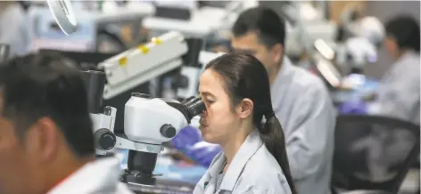  ?? Josie Norris / The Chronicle ?? Somalen Ton inspects a circuit board in the quality assurance department of Tempo Automation, a prototype manufactur­er.