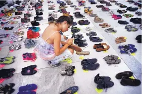  ?? RAMON ESPINOSA/ASSOCIATED PRESS ?? A woman places, in front of the Puerto Rico Capitol, in San Juan, on Friday, one of hundreds of shoes in memory of those killed by Hurricane Maria last September.