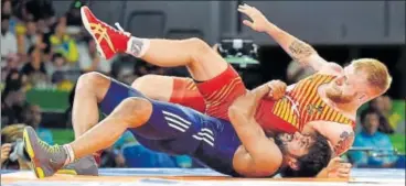  ?? PTI ?? India's Bajrang Punia (in blue) grapples with Wales' Kane Charig in men's freestyle 65 kg final on Friday.