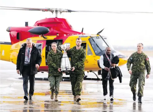  ?? —THE CANADIAN PRESS ?? CFL commission­er Randy Ambrosie, left, oversees the arrival of the Grey Cup at Canadian Forces Base Edmonton last week. Ambrosie is looking for new ways to attract younger fans to Canadian pro football.