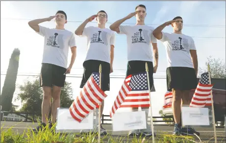  ?? BEA AHBECK/NEWS-SENTINEL ?? Runners from Travis Air Force Base: Staff Sgt. Hongtao Wu and airmen first class Caleb Hopper, Alex Shepard, and Mario Hernandez salute flags, each with a note with an image and biography of a fallen soldier attached, during the first day of the Run...