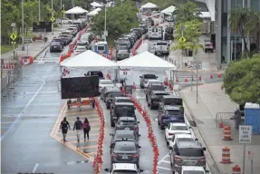  ?? JOE RAEDLE/GETTY IMAGES ?? Cars line up as drivers wait to be tested for COVID-19 on Monday at the Miami Beach Convention Center in Miami Beach, Fla.