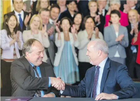  ??  ?? B.C. Green Party Leader Andrew Weaver and B.C. NDP Leader John Horgan shake hands after officially signing their agreement at the legislatur­e on Tuesday, with members of both caucuses showing support. The pact lists the policies the two parties have...