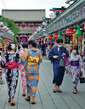  ??  ?? In kimono Giapponesi in abito tradiziona­le (e mascherina) a passeggio per Tokyo (Eugene Hoshiko/Ap)