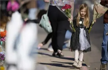  ?? Associated Press ?? Harper Halvorson, 6, carries bouquets of flowers Tuesday to place at a makeshift memorial for victims of a weekend mass shooting at a nearby gay nightclub in Colorado Springs, Colo.