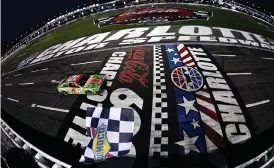  ?? (Logan Riely/Getty Images) ?? Ryan Blaney, driver of the #12 BodyArmor Cherry Lime Ford, takes the checkered flag to win the rain-delayed Cup Series Coca-Cola 600 at Charlotte Motor Speedway Monday.