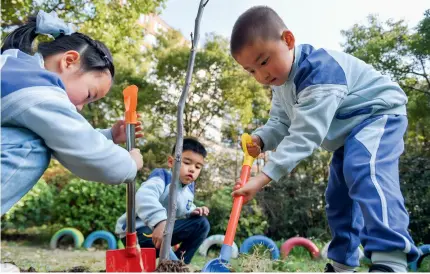  ?? ?? Children at a kindergart­en in Nanjing, Jiangsu Province, plant trees on March 11