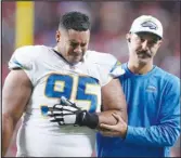  ?? ?? Chargers defensive tackle Christian Covington (95) is helped off the field during the second half against the San Francisco 49ers, Sunday, in Santa Clara.