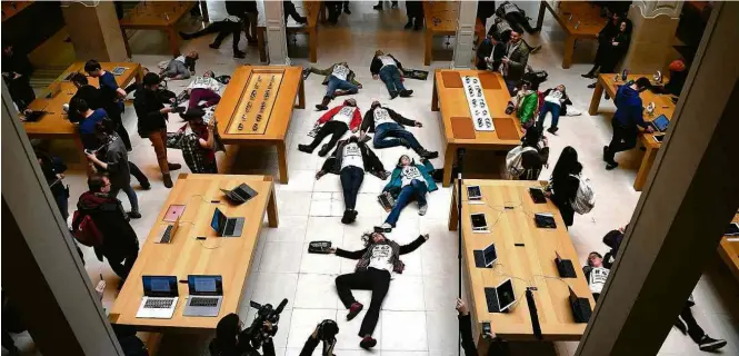  ?? Eric Feferberg/AFP ?? » QUE TIRO FOI ESSE? Ativistas protestam em loja da Apple da Opéra, em Paris, contra a prática da empresa de transferir lucros para a Irlanda em busca de benefícios fiscais