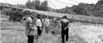  ??  ?? Dennis (fourth left) with the school staff and villagers looking at the badly damaged bridge.