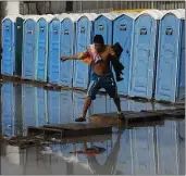  ?? REBECCA BLACKWELL — THE ASSOCIATED PRESS ?? A migrant leaves a flooded shower and toilet area at a sports complex sheltering thousands of Central American migrants in Tijuana, Mexico.