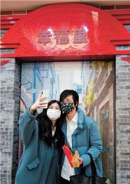  ??  ?? Wang, 32, and his wife Shi, 30, take a selfie as Wang holds their marriage certificat­es at a marriage registry office in Shanghai on Valentine’s Day amid the novel coronaviru­s outbreak. — Reuters