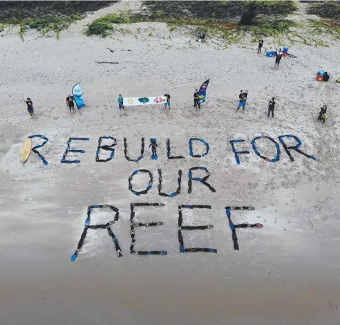  ?? Picture: STEWART McLEAN ?? MESSAGE: Campaigner­s spell out 'Rebuild for our Reef' with diving fins on Yorkeys Knob beach.