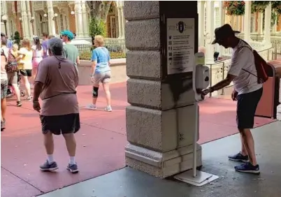  ?? DEWAYNE BEVIL/ORLANDO SENTINEL ?? Guests use hand sanitizer stations before entering Disney’s Magic Kingdom. Disney World has taken precaution­s against coronaviru­s.