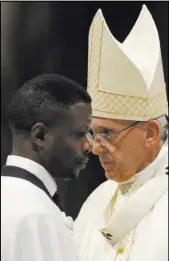  ?? Gregorio Borgi The Associated Press ?? Former Nigerian-born beggar John Ogah walks past Pope Francis after being baptized Saturday during an Easter vigil ceremony in St. Peter’s Basilica at the Vatican.