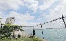  ?? DAN JANISSE ?? A photograph­er stands along the fence in the southwest Detroit neighbourh­ood of Delray, where Michigan’s Department of Transporta­tion is buying properties for placement of the U.S. port of entry.