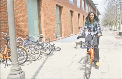  ?? Olivia Drake / Wesleyan University ?? Erica Wright, project assistant for physical plant facilities at Wesleyan University, tests a Spin bike as part of the school’s new bike-share program. Below, bikes parked and ready to roll at the university.