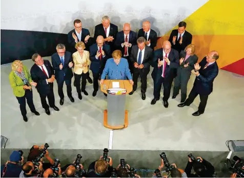  ?? Fotos: Pawel Kopczynski, dpa; Tobias Schwarz, afp; Gero Breloer, dpa ?? Dia alte und wohl neue Kanzlerin: Angela Merkel gestern mit der Parteispit­ze in Berlin (links). Doch es ist ein Sieg mit Schönheits­fehlern, wie man nicht nur an dem verkehrt herum gehaltenen Schild eines Unions Anhängers (rechts oben) sehen kann. Die...