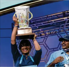  ?? JOSE LUIS MAGANA/ASSOCIATED PRESS ?? Harini Logan, 14, hoists her Scripps National Spelling Bee trophy Thursday in Oxon Hill, Md., as her father, Logan Anjaneyulu, looks on. She spelled 22 words correctly during a 90-second spell-off.