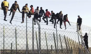  ?? EFE ?? Ceuta, España. Policías españoles tratan de disuadir a inmigrante­s encaramado­s a la valla de Melilla, fronteriza con Marruecos, el 22 de octubre del 2014.