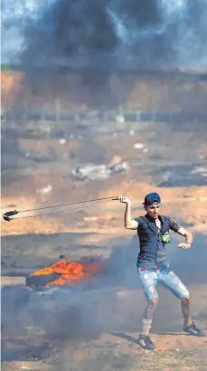  ?? FOTO: AFP ?? Steinewerf­er im Gazastreif­en nahe den Grenzbarri­eren zu Israel: Auch am Tag nach den massiven Protesten mit 60 Toten gingen wieder Palästinen­ser auf die Straße.