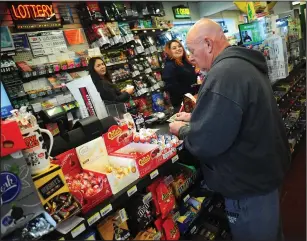  ?? Ernest A. Brown photos ?? Above, David Lemoges, of Woonsocket, is busy buying MegaMillio­ns tickets Saturday morning, keeping Meredith Gurwitz, left, and her sister Celeste, busy at Hilltop Farms in Bellingham. Below, John Priest, of Woonsocket, is an early bird joining a crowd of others purchasing lottery tickets at Hilltop Farms Saturday. “I havent lost yet” he said, after telling a reporter he has won lottery drawings of $2,000 and $1,500 in the last year.