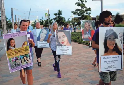  ?? BRYAN TERRY/THE OKLAHOMAN ?? People hold pictures of loved ones lost to addiction Tuesday during a walk organized by Team Sharing Inc. in recognitio­n of Internatio­nal Overdose Awareness Day at Scissortai­l Park in Oklahoma City.