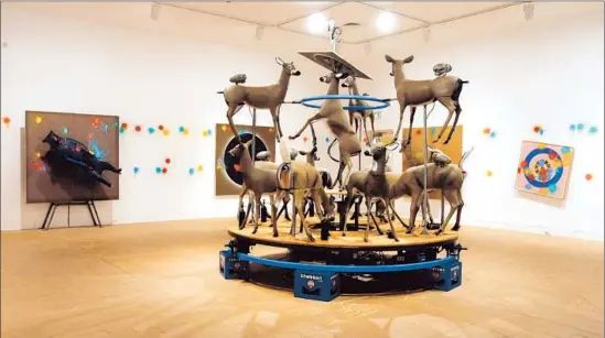  ?? Photog raphs by Don Bartletti
Los Angeles Times ?? RICHARD JACKSON’S
“Deer Beer,” a 1998 work re-created for the exhibition, is a carousel of deer that shoot paint at targets in the room, a reversal of hunting roles.