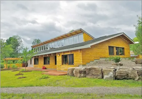  ?? PHOTOS: DOMINIQUE PARIZEAU/ SPECIAL TO THE GAZETTE ?? The south-facing second-storey windows of the 2,700-square-foot house let in winter warmth and deflect heat in summer. The earth and stone end-wall berms conserve heat, and store the building’s mechanical­s.