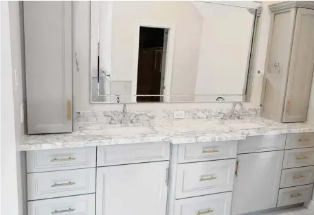 ?? Courtesy of Lone Star Remodeling ?? Neutral gray cabinets with marble countertop­s offer a timeless and classic, yet modern design.