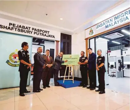  ?? BERNAMA PIC ?? Home Minister Datuk Seri Saifuddin Nasution Ismail (centre) signing a plaque at the launch of the Immigratio­n Department’s passport office at Shaftsbury Mall in Putrajaya yesterday. With him is Immigratio­n director-general Datuk Ruslin Jusoh (third from right).