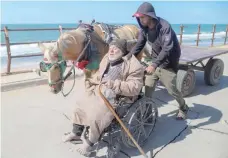  ?? — Reuters ?? A Palestinia­n man sitting in a wheelchair is assisted while moving southward after he fled north Gaza, following an Israel raid on Al Shifa Hospital and the area around it in the central Gaza Strip.