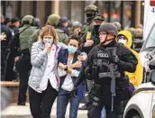  ?? CHET STRANGE GETTY IMAGES ?? Health care workers walk out of the supermarke­t after a gunman opened fire inside on Monday.